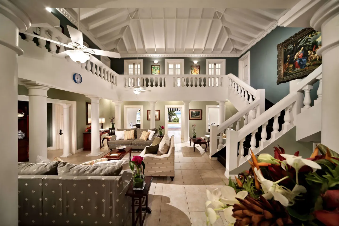 Living room in a 5 Bedroom Garden View Villa at Half Moon with sofas, columns, and a grand staircase.