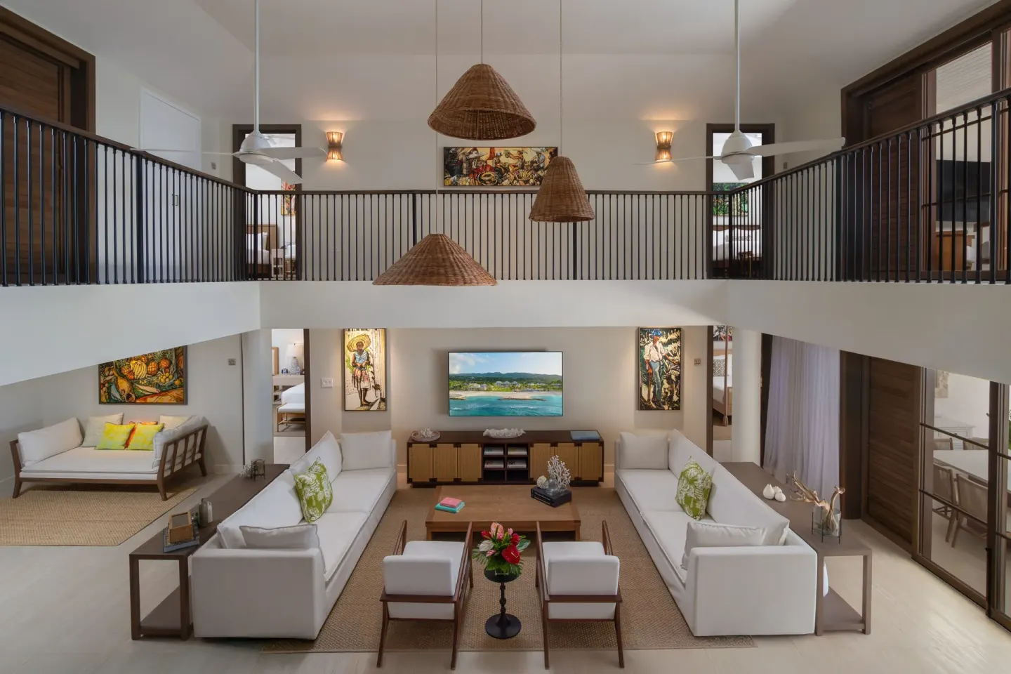 Ocean-view villa lounge with sofas, loft balcony, and guest rooms at Half Moon.