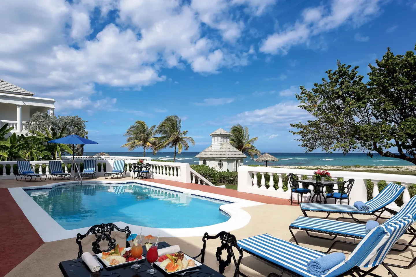 Ocean-view villa pool terrace with loungers and sea beyond at Half Moon.