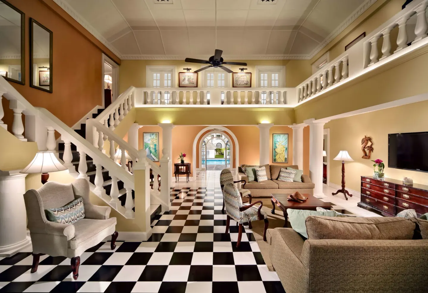 Two-story villa living room with checkered floor and staircase at Half Moon.