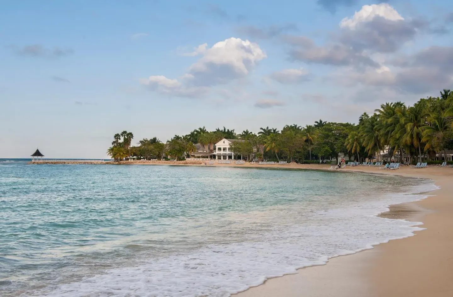 Beach shoreline with turquoise water, palms, and lounge chairs at Half Moon.