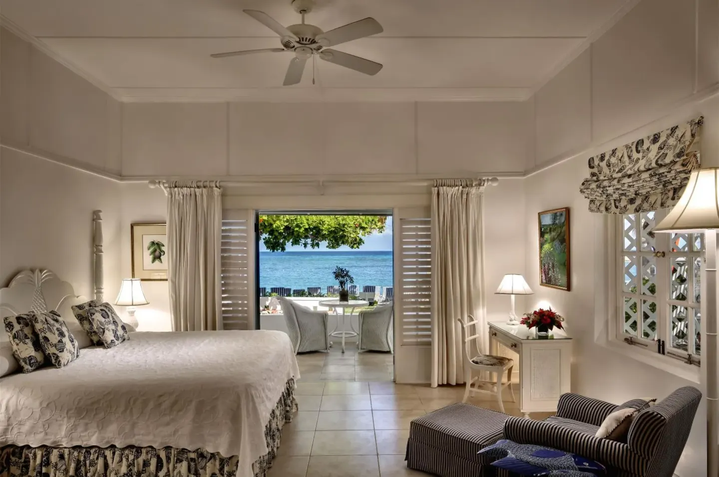 Ocean View room with king bed, desk, striped chair, and patio view at Half Moon.