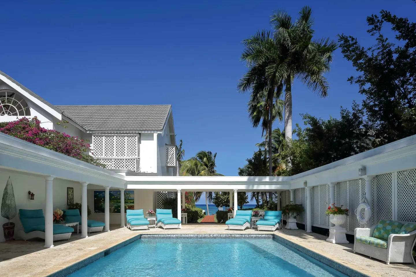 Suite pool courtyard with blue loungers and ocean glimpse at Half Moon.