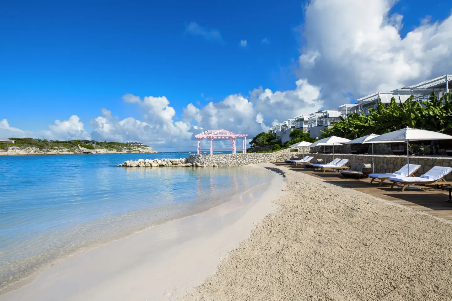 Sandy beach with loungers, umbrellas and calm blue water at Hammock Cove Antigua.