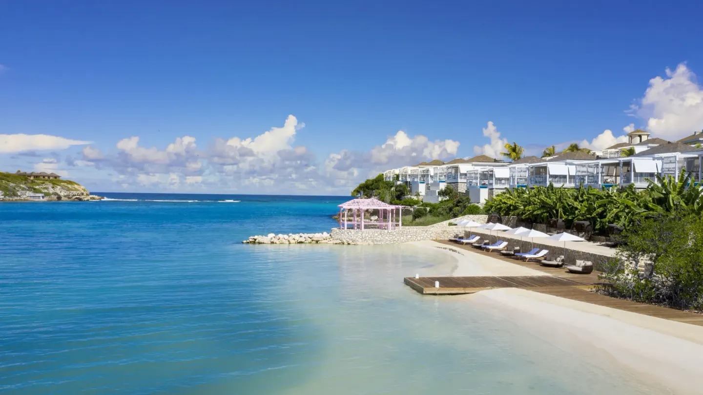 Calm beach, turquoise water, loungers, and resort buildings at Hammock Cove Antigua.