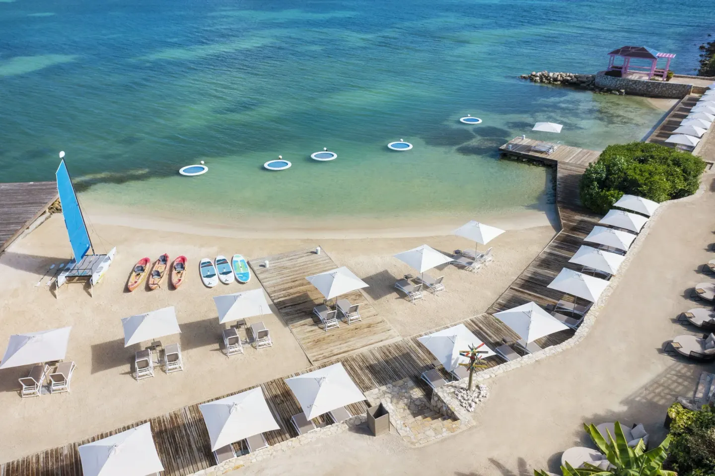 Overhead view of umbrellas, loungers, water floats and kayaks at Hammock Cove Antigua.
