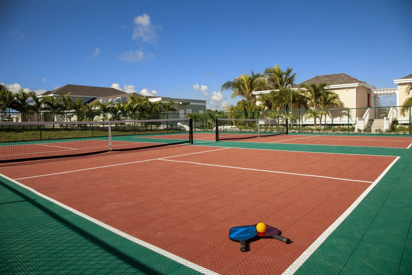Pickleball court with paddles and ball in the foreground at Hammock Cove Antigua.