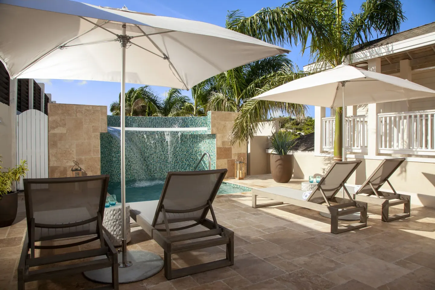 Private patio with plunge pool, waterfall, umbrellas, and loungers at Hammock Cove Antigua.