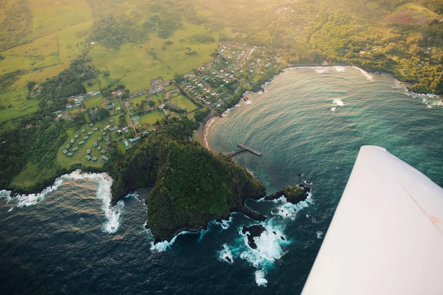 Aerial view of Hana Bay shoreline and a wingtip near Hana-Maui Resort.