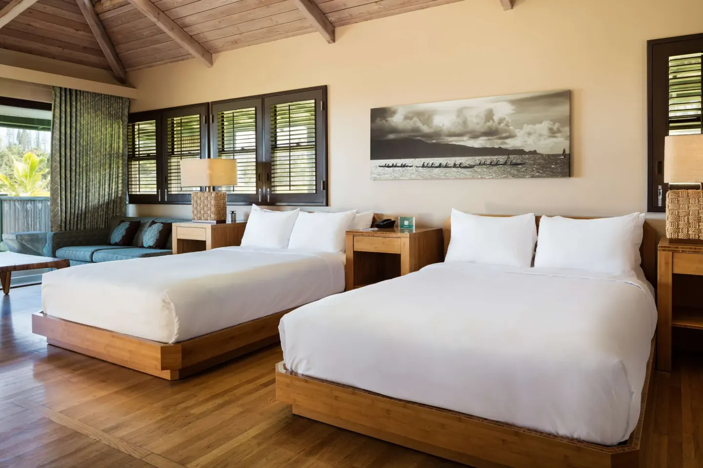 Guest room with two beds, wood ceiling, shutters, and sitting area at Hana-Maui Resort.