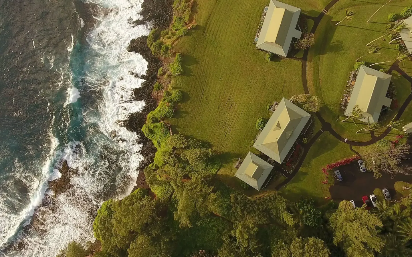 Aerial view of oceanfront cottages and surf along the coast at Hana-Maui Resort.