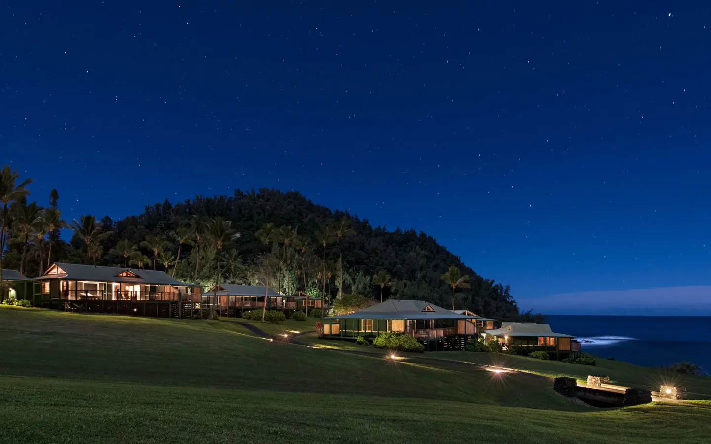 Oceanfront bungalows on a lawn under a starry sky at Hana-Maui Resort.