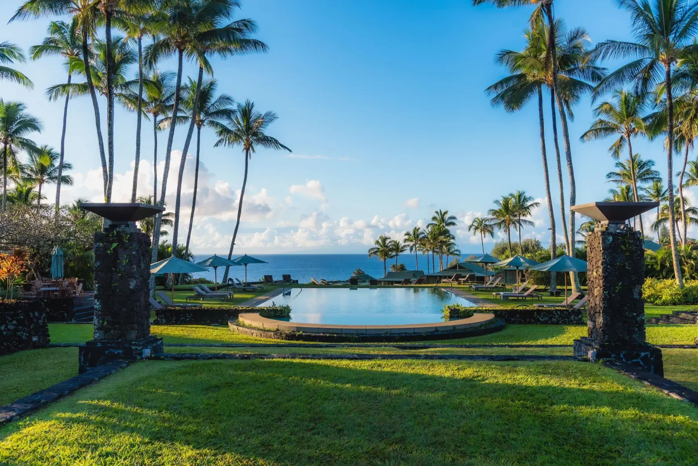 Palm-framed pool and ocean view from the grounds at Hana-Maui Resort.