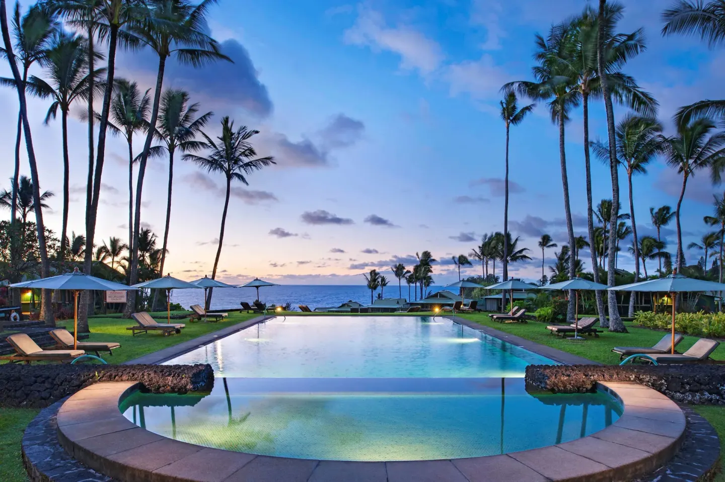 Oceanfront pool with lounge chairs and palms at Hana-Maui Resort.