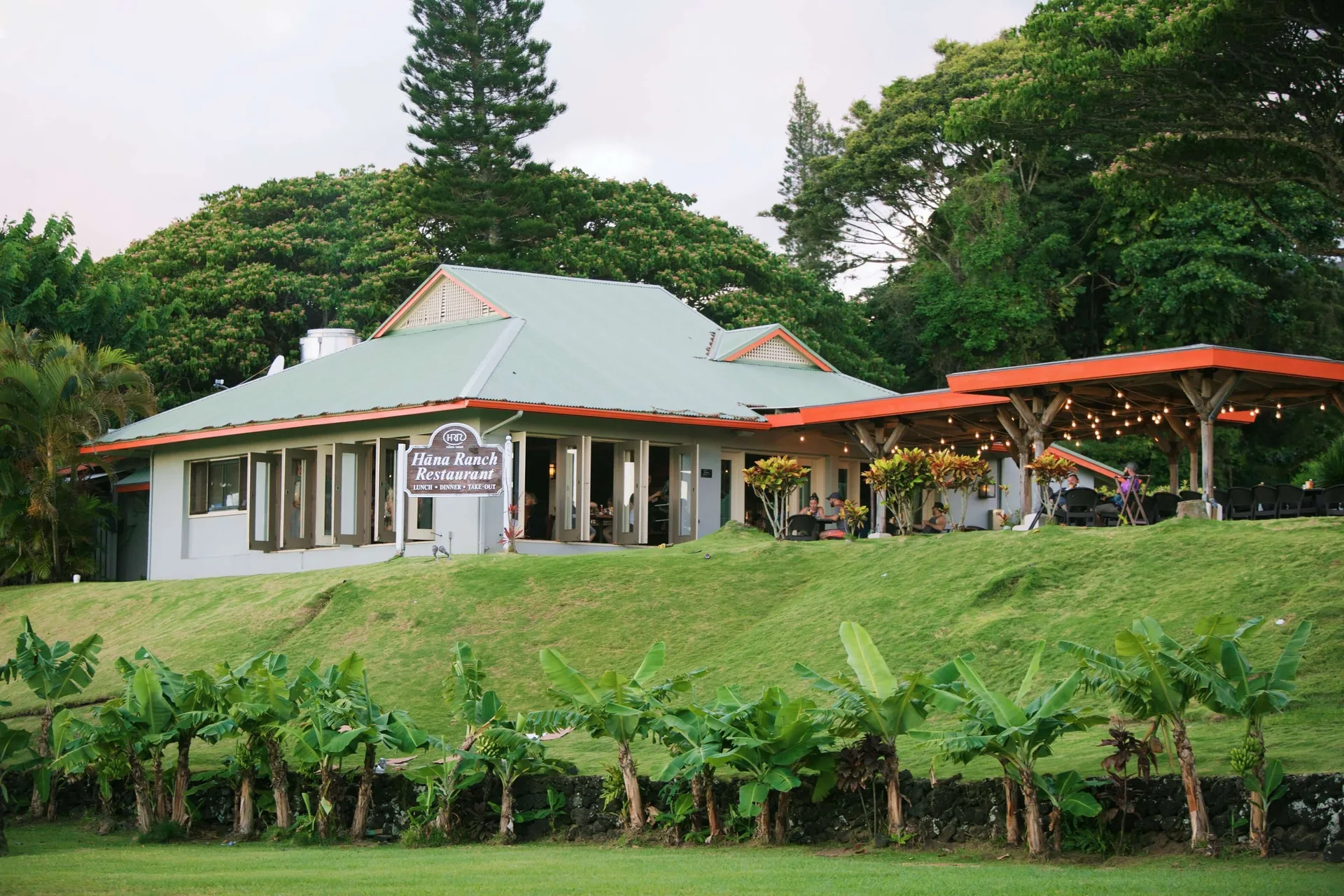 Hana Ranch Restaurant building with patio seating and lawn at Hana-Maui Resort.