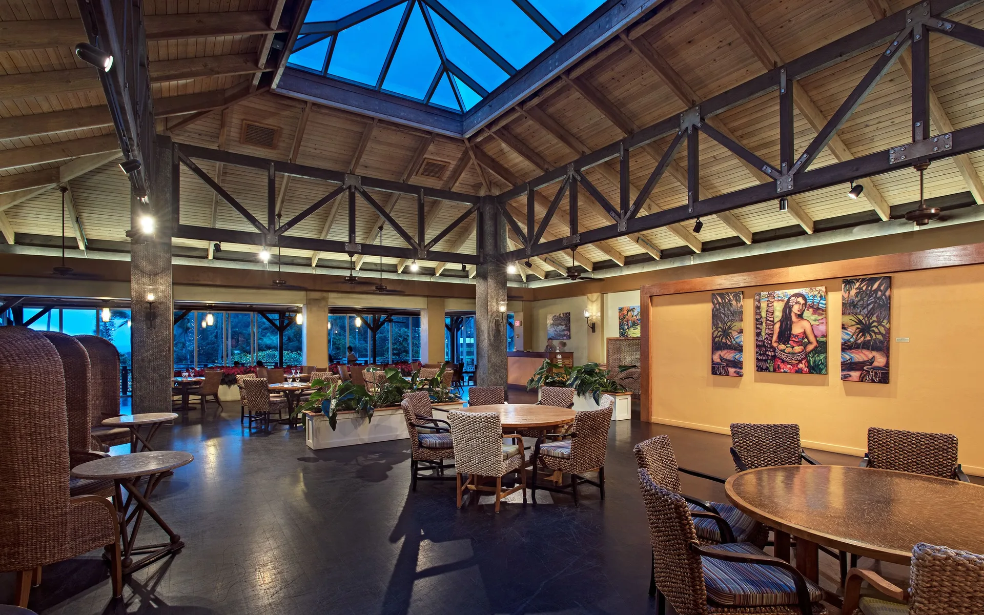 Open dining room with wicker chairs, artwork, and skylit wood ceiling at Hana-Maui Resort.