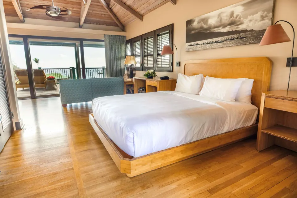 King bed in an Ocean View Bungalow with balcony doors at Hana-Maui Resort.