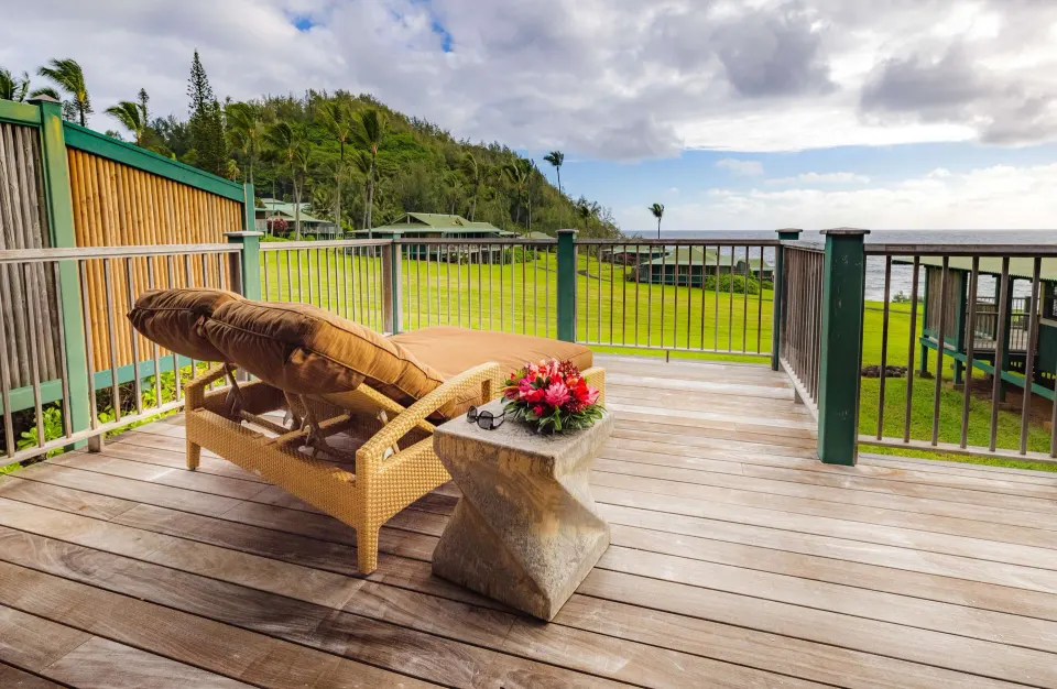 Ocean View Bungalow deck with lounge chair and coastal view at Hana-Maui Resort.