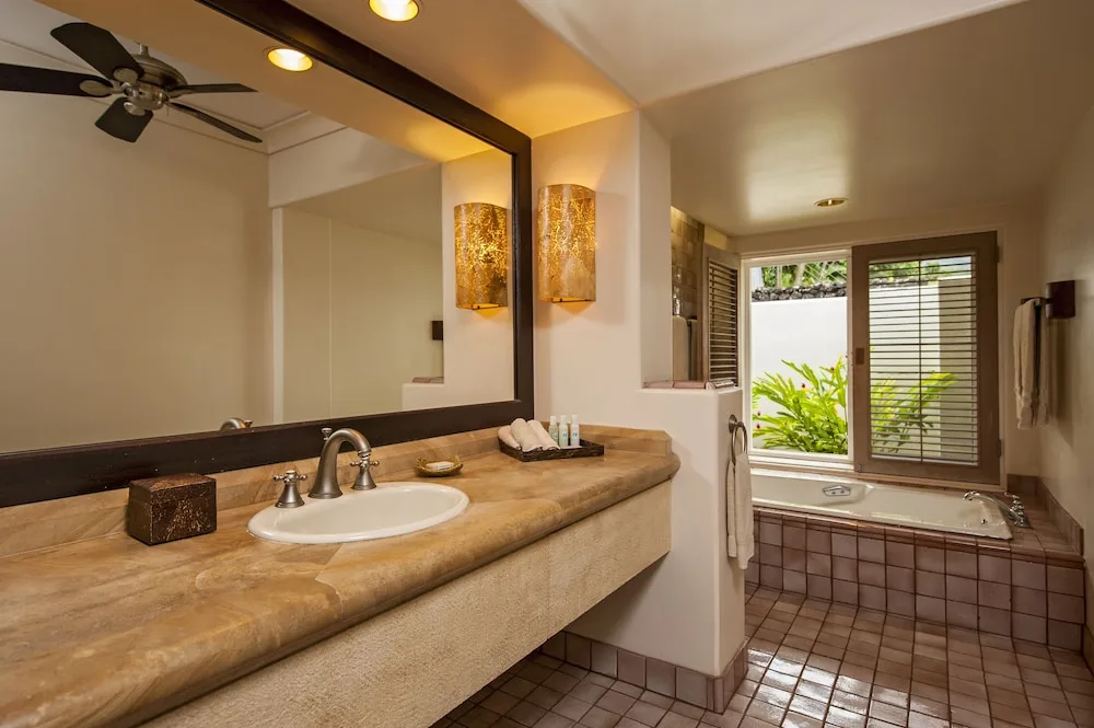 Garden View Suite bathroom with vanity, tub, and shuttered garden window at Hana-Maui Resort.