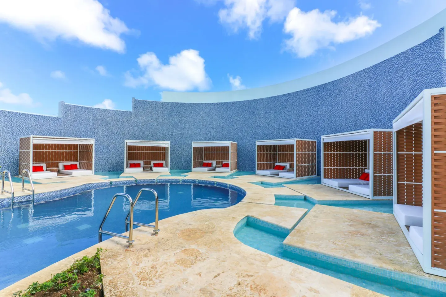 Curved pool area with cabanas and blue mosaic wall at Harbor Club St. Lucia.