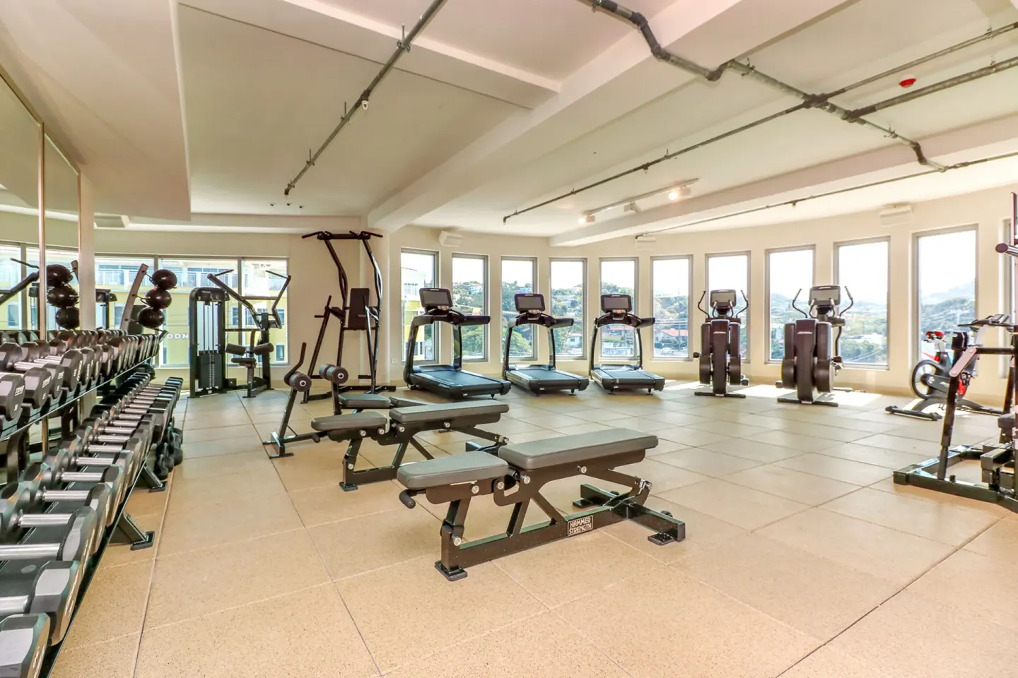 Fitness center with treadmills, benches, and dumbbell racks at Harbor Club St. Lucia.