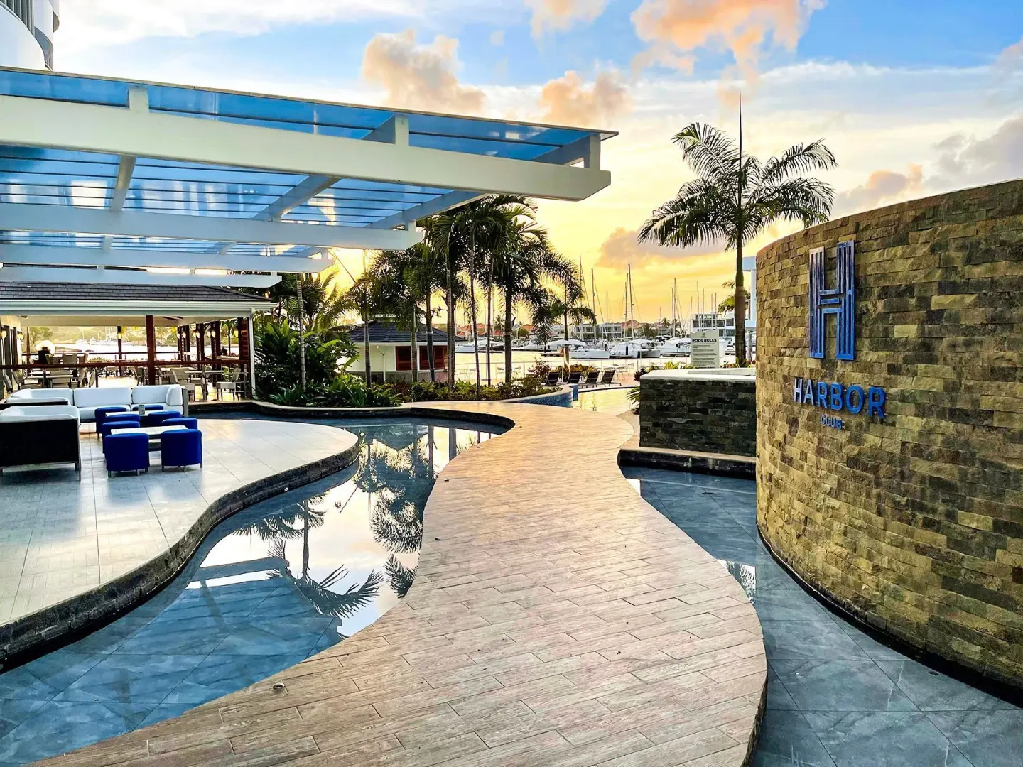 Curved walkway, reflective pools, marina, and Harbor Club St. Lucia sign at Harbor Club St. Lucia.