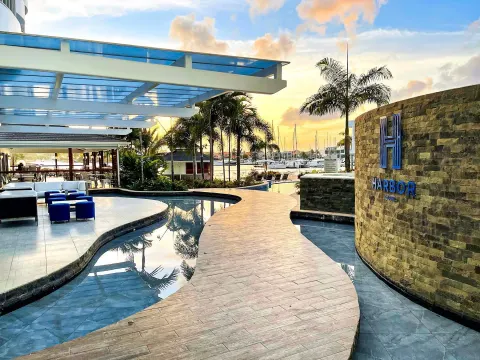 Curved walkway, reflective pools, marina, and Harbor Club St. Lucia sign at Harbor Club St. Lucia.