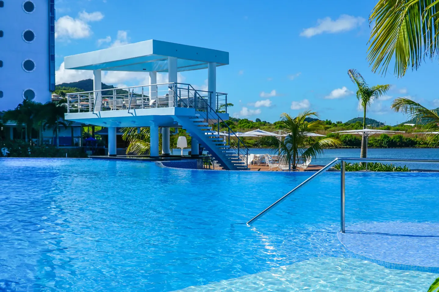 Pool with swim-up railings, palm trees, and a raised deck at Harbor Club St. Lucia.