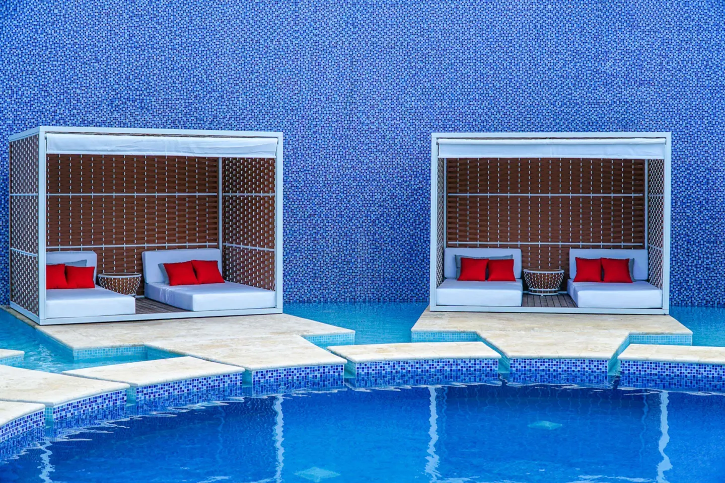 Poolside cabanas with red pillows at Harbor Club St. Lucia.