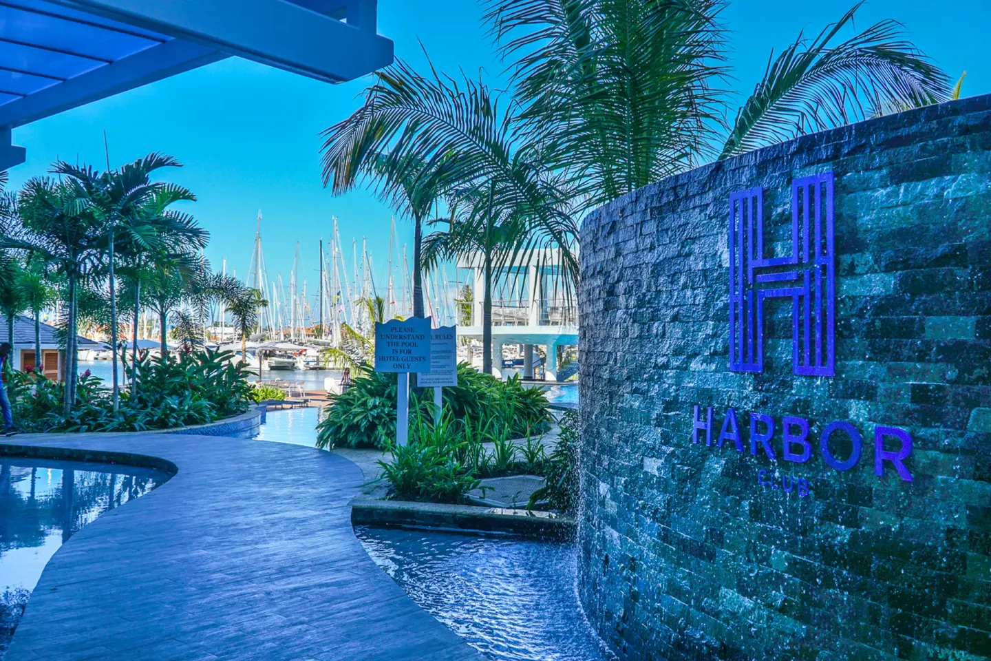 Harbor Club St. Lucia sign beside pool landscaping and marina views.