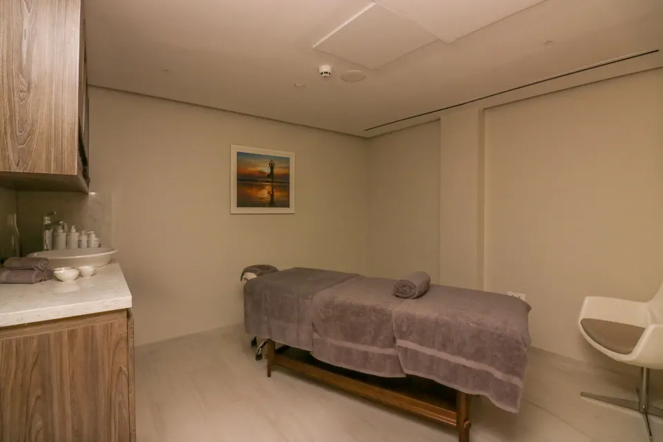 Spa treatment room with massage table and white chair at Harbor Club St. Lucia.