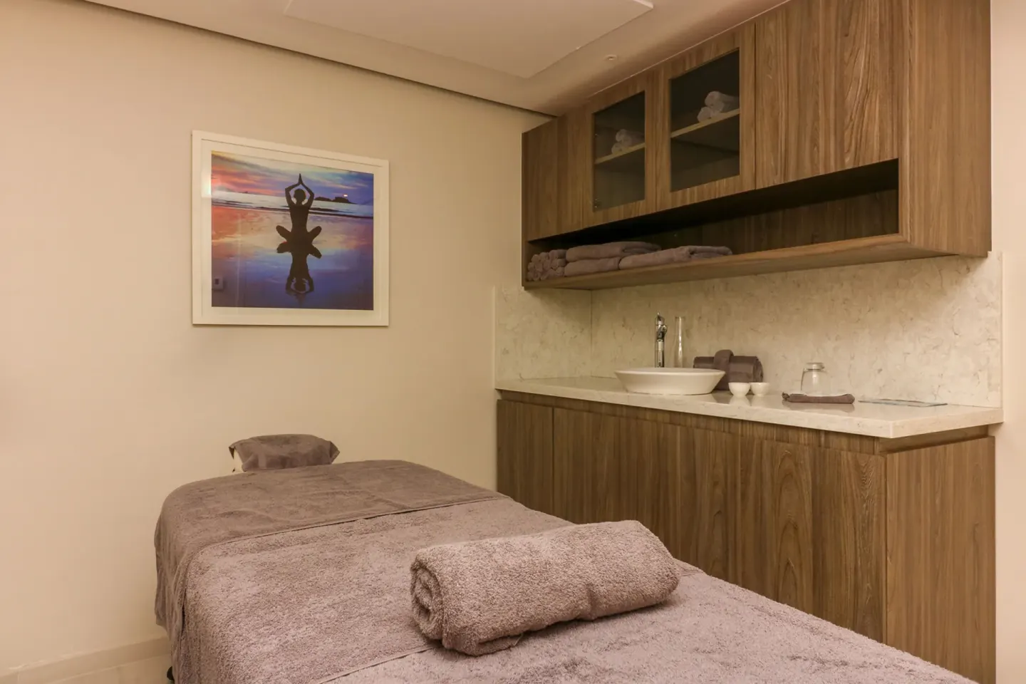 Spa room with massage table, wood cabinets, and sink at Harbor Club St. Lucia.