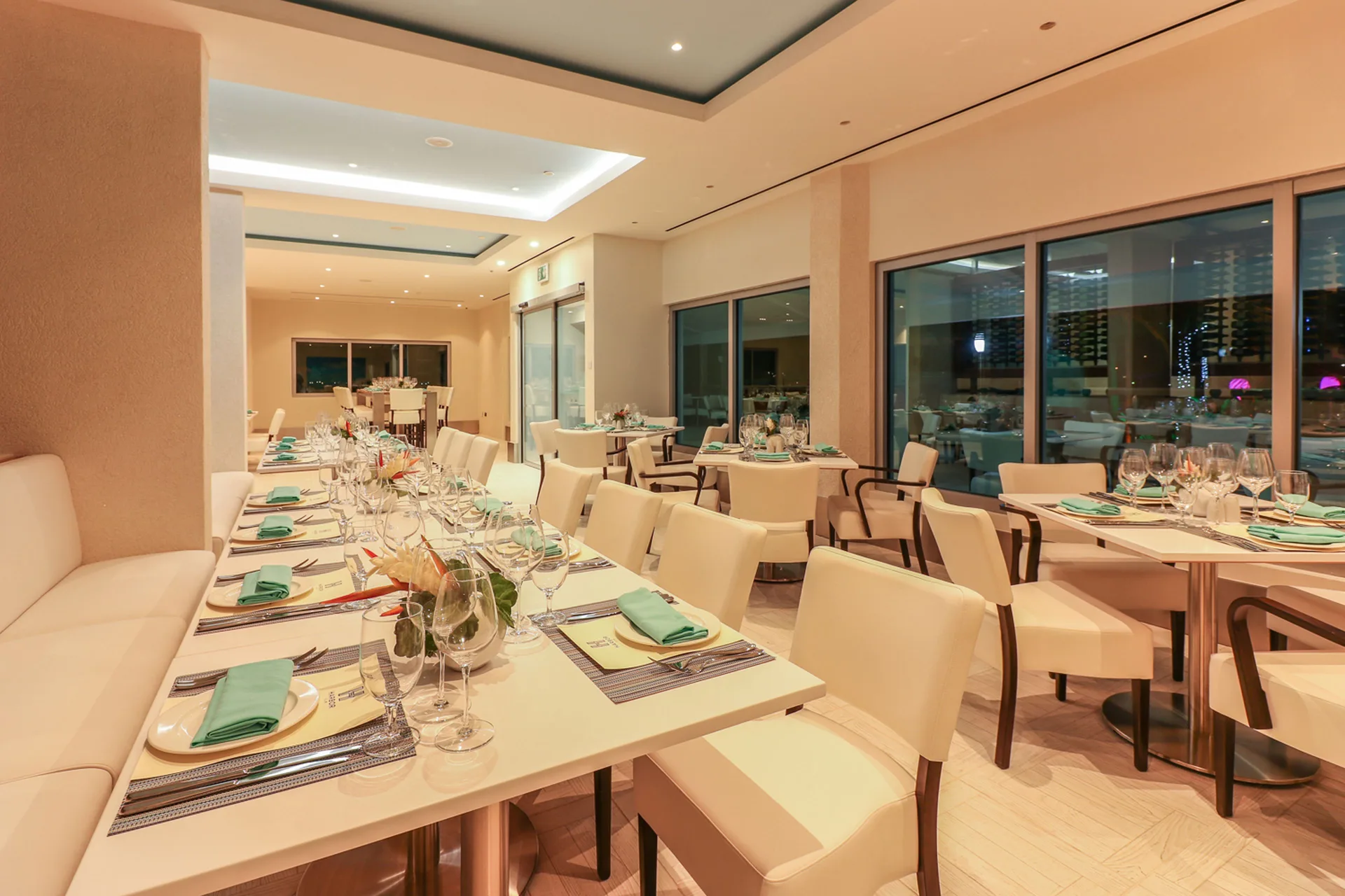Set dining tables with turquoise napkins inside Harbor Club St. Lucia.