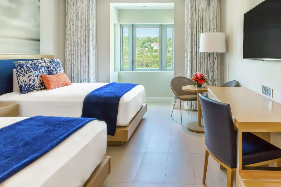 Island View room with two beds, desk, and window at Harbor Club St. Lucia.