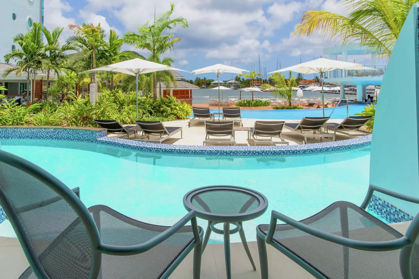 Swim-up room patio with chairs beside the pool at Harbor Club St. Lucia.