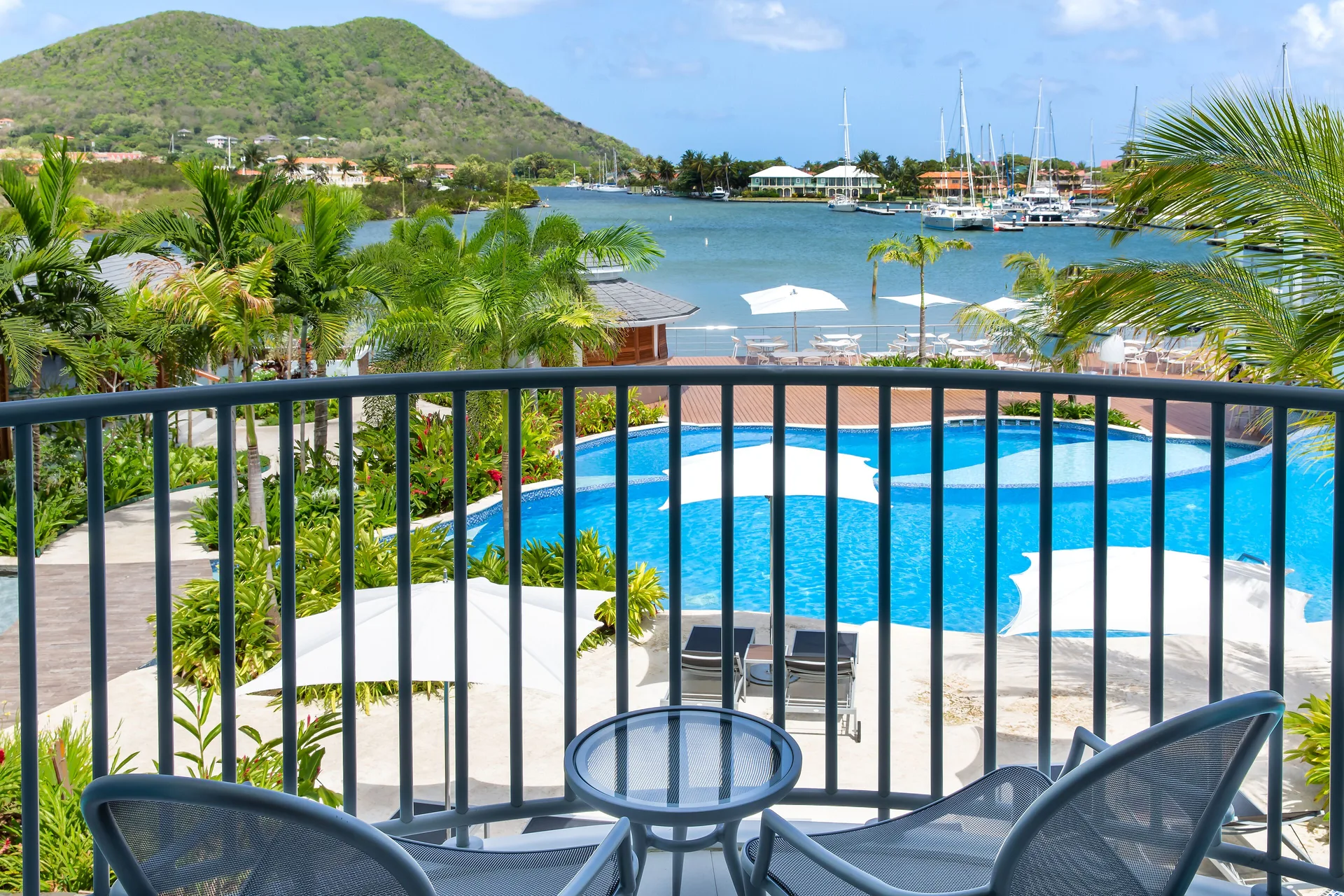 Balcony view of pool, palms, and marina at Harbor Club St. Lucia.