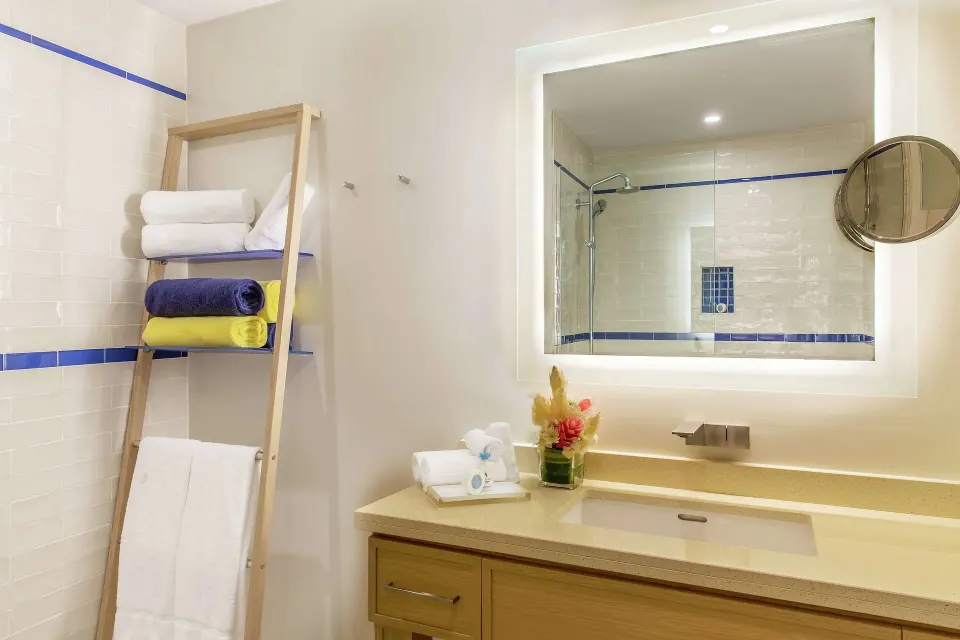 Guest bathroom vanity with lit mirror and towel ladder at Harbor Club St. Lucia.