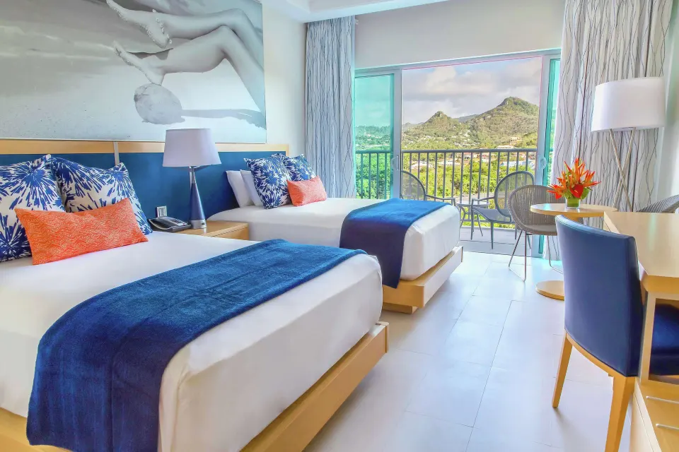 Two beds in a guest room with balcony mountain view at Harbor Club St. Lucia.