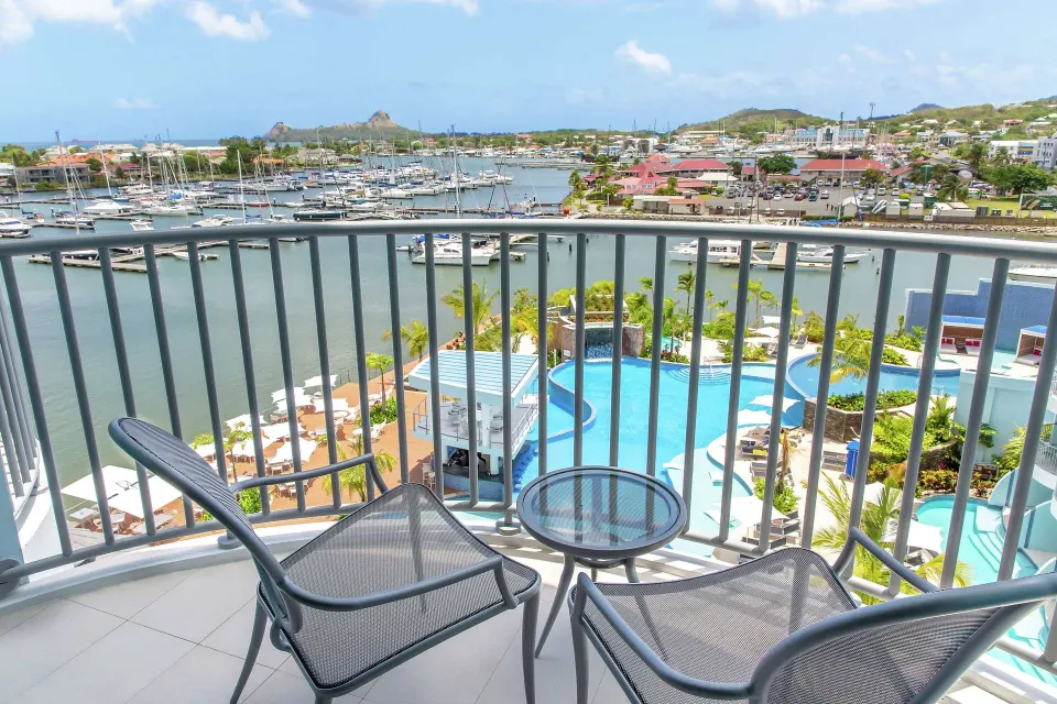 Captain Suite balcony with chairs overlooking marina and pool at Harbor Club St. Lucia