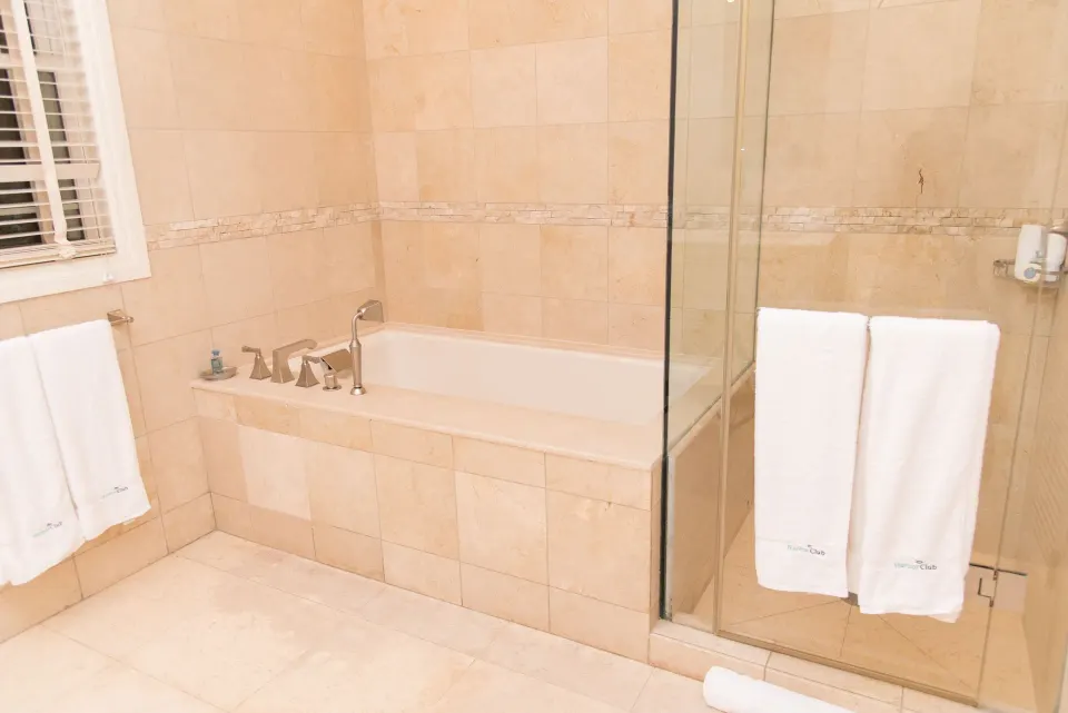 Captain Suite bathroom with tiled soaking tub and glass shower at Harbor Club St. Lucia