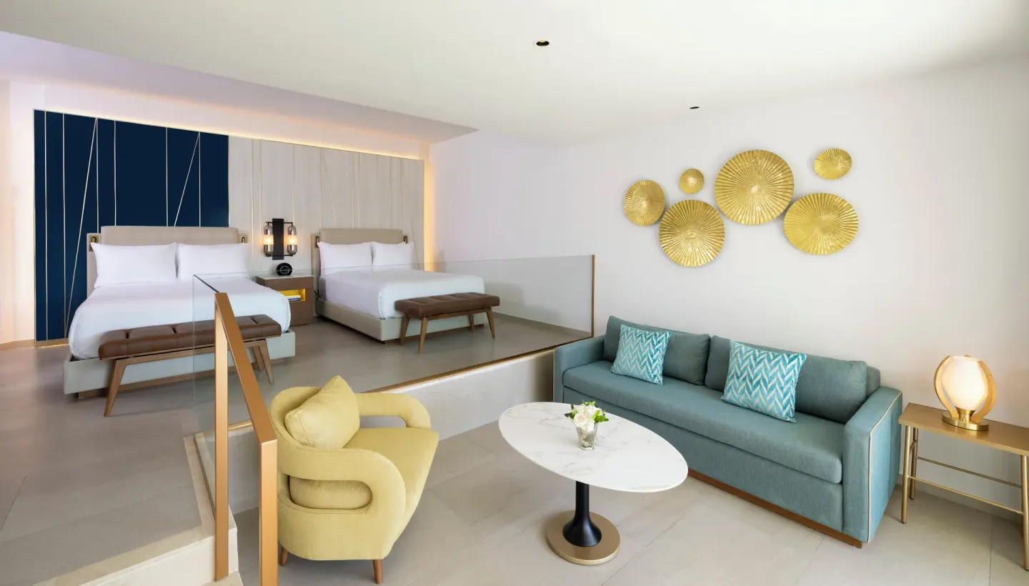 Two queen beds and a sitting area in a suite at Hard Rock Hotel & Casino Punta Cana.