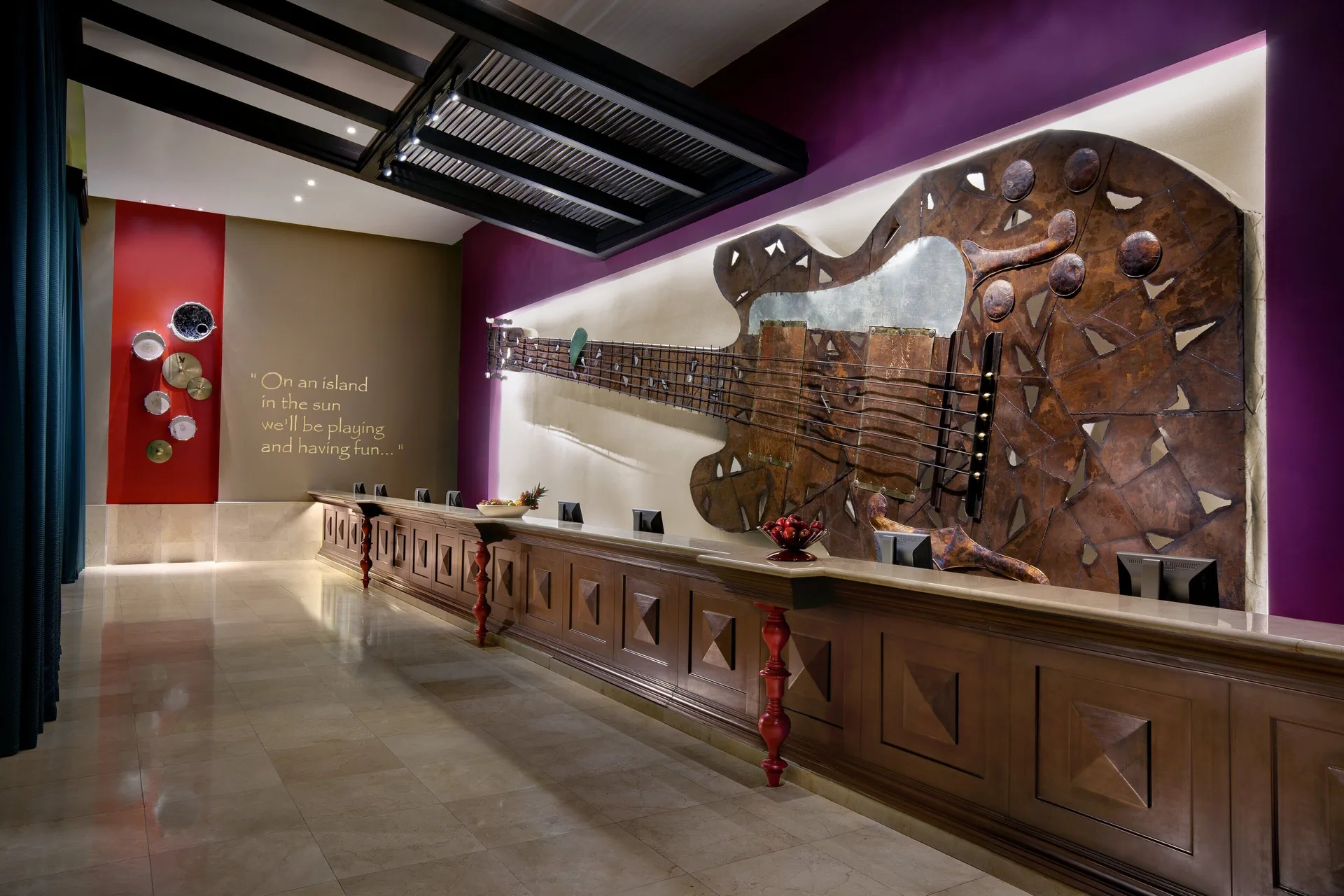 Long reception desk with a large guitar wall sculpture at Hard Rock Hotel & Casino Punta Cana.