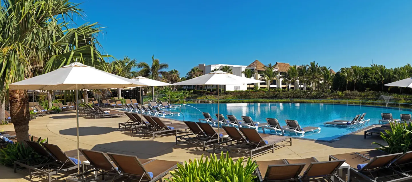 Sunny resort pool with loungers and umbrellas at Hard Rock Hotel & Casino Punta Cana.