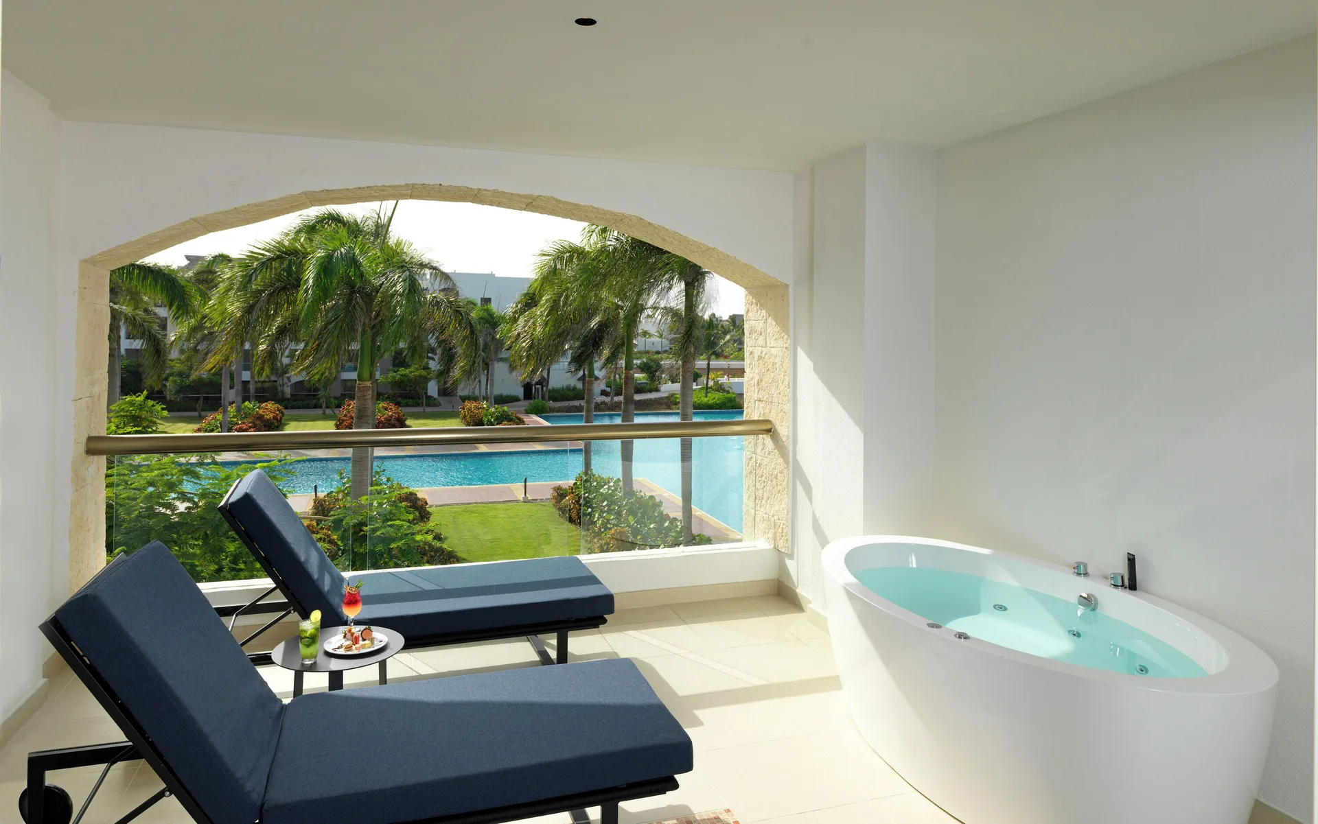 Caribbean Sand Suite terrace with loungers and soaking tub at Hard Rock Hotel & Casino Punta Cana overlooking tropical gardens and beachfront.