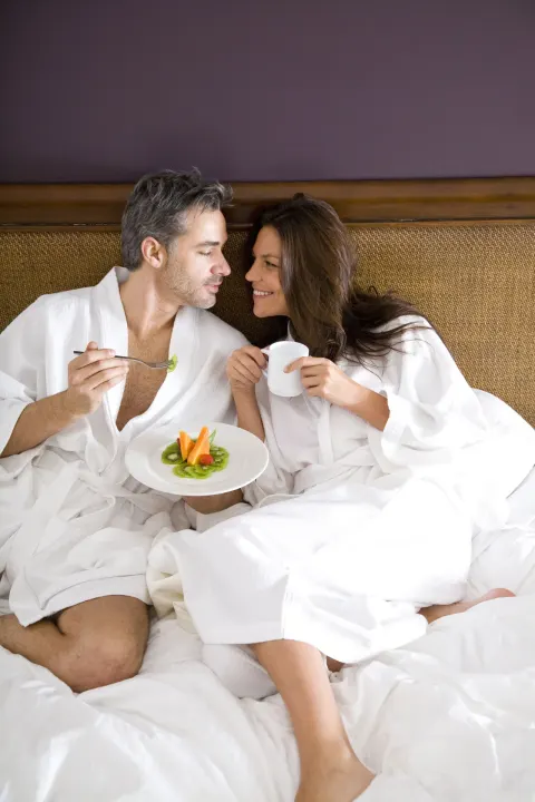 Couple in white robes share breakfast in bed at Hard Rock Hotel Cancun.