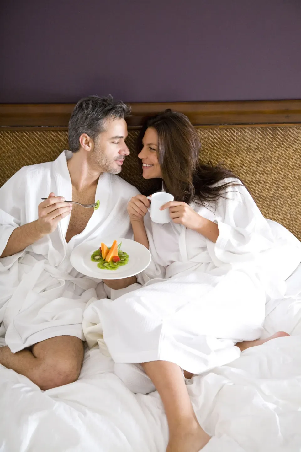 Couple in white robes share breakfast in bed at Hard Rock Hotel Cancun.