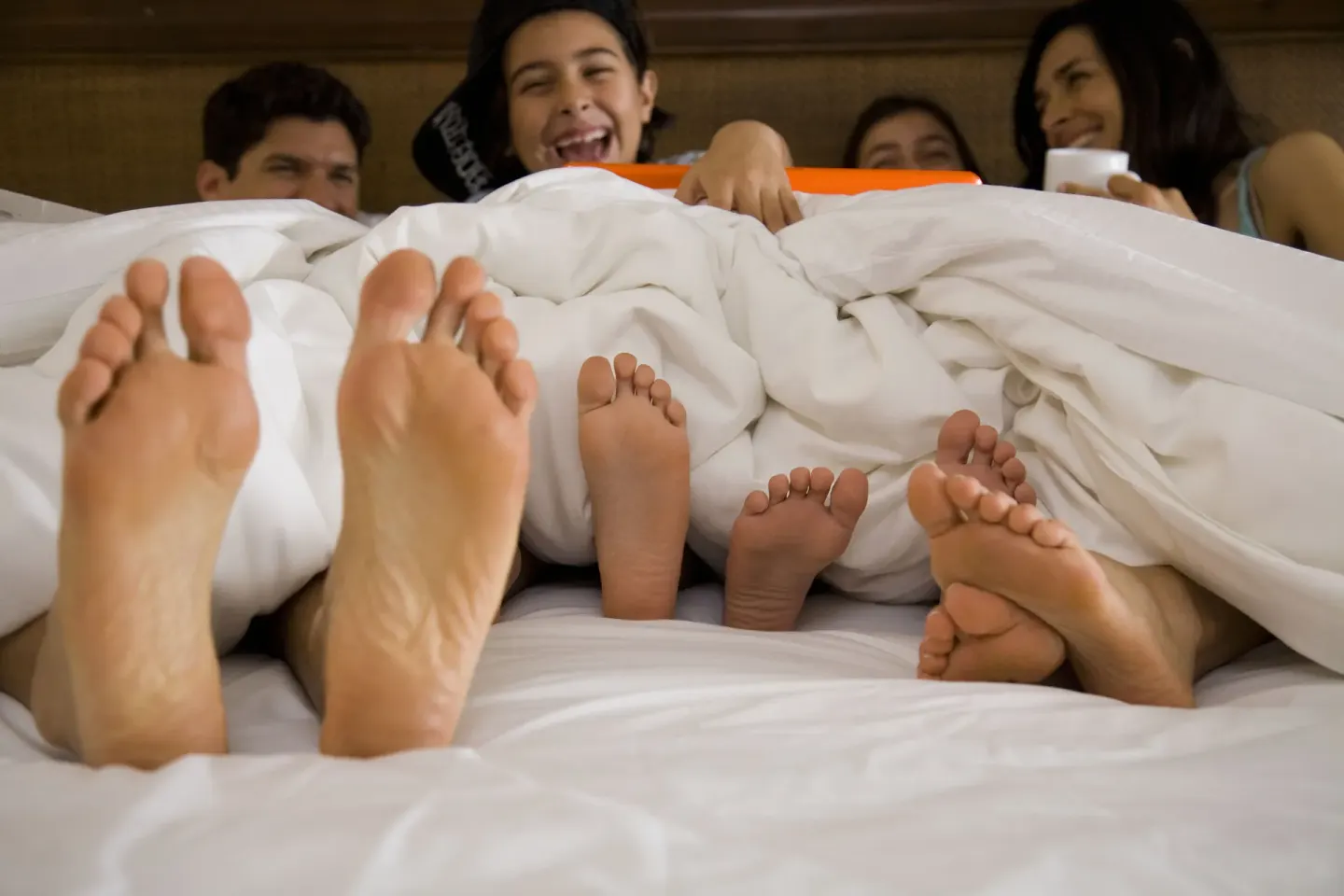Family laughs under white bedding in a guest room at Hard Rock Hotel Cancun.