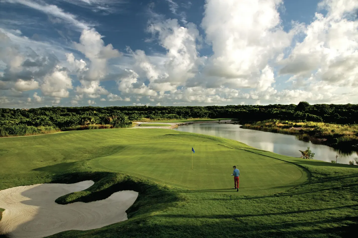 Wide golf course view with a green, sand trap, and water near Hard Rock Hotel Cancun.