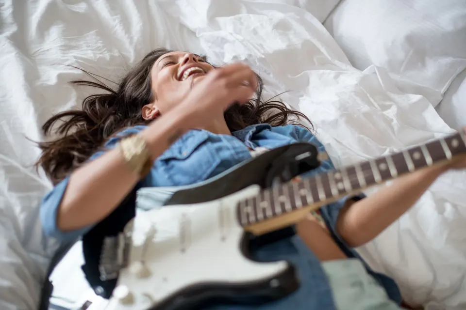 Guest relaxes on white bedding with an electric guitar at Hard Rock Hotel Cancun.