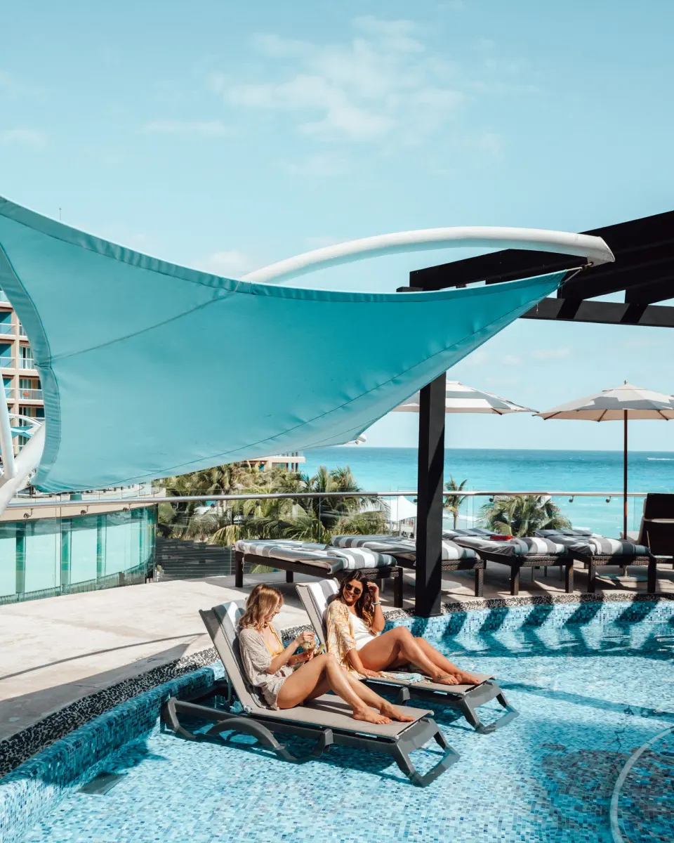 Pool loungers under a turquoise shade canopy at Hard Rock Hotel Cancun.